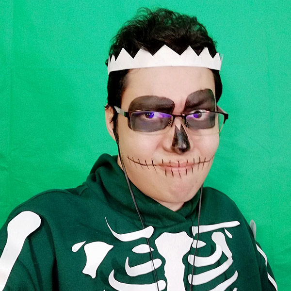 GamerZakh with black skeleton makeup wearing a green hoodie in front of a greenscreen.